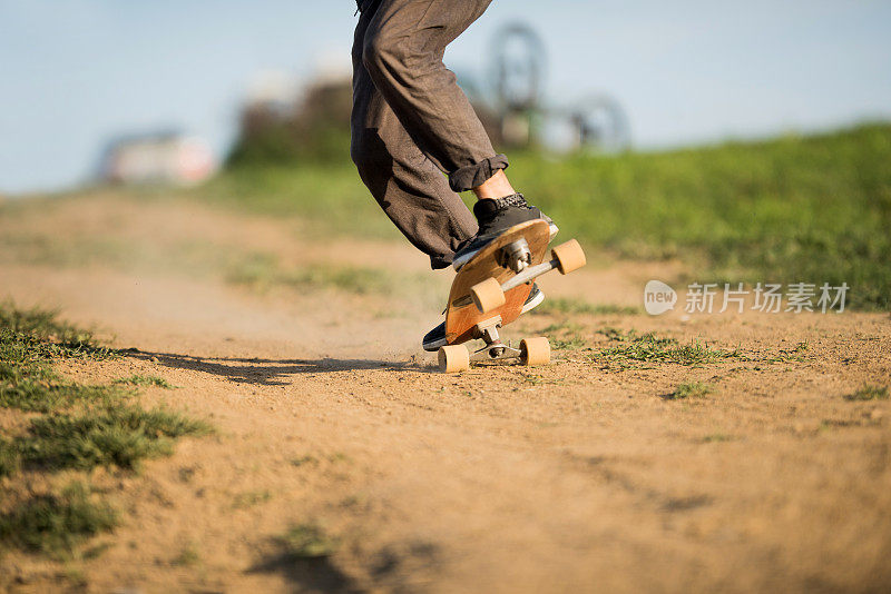 一个面目全非的男人白天在一条土路上玩滑板。