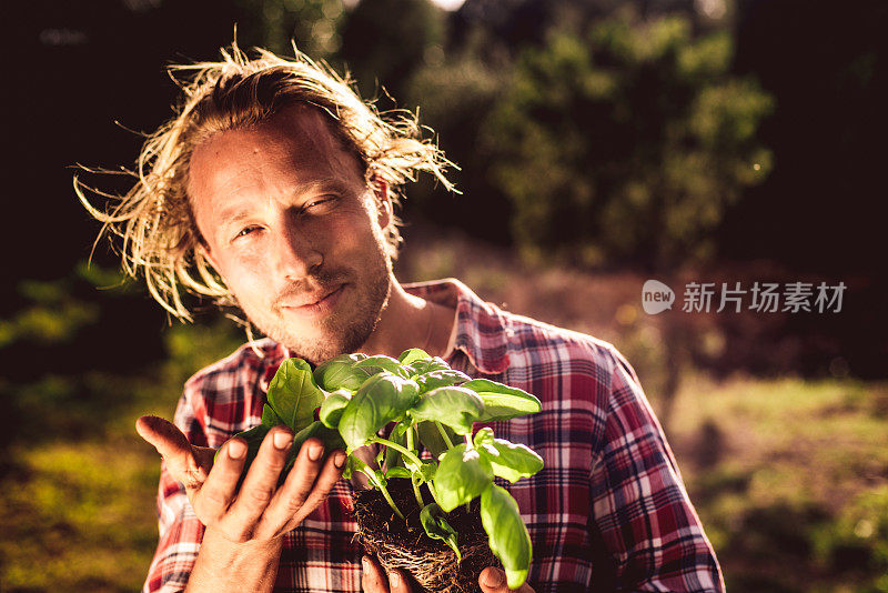 一个年轻的农民在闻一片年轻的罗勒叶子