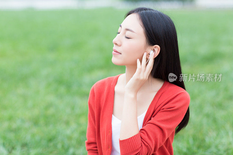 年轻女孩用智能手机的耳机听音乐