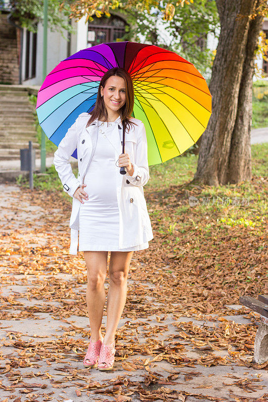 快乐孕妇撑五彩伞在雨中