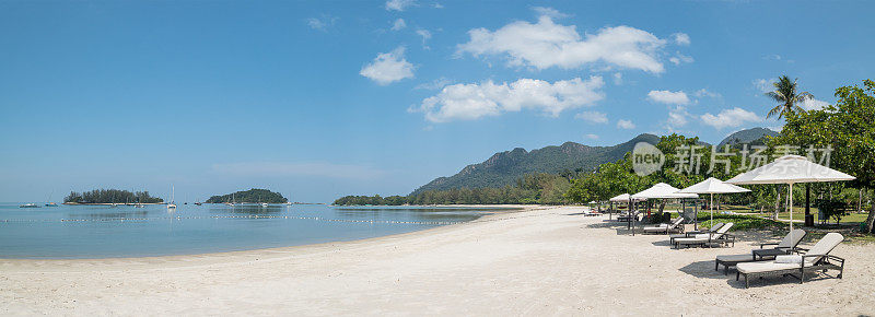 热带岛屿海滩与太阳伞和太阳床