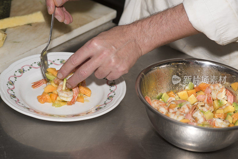 厨师双手准备装盘的热带水果沙拉