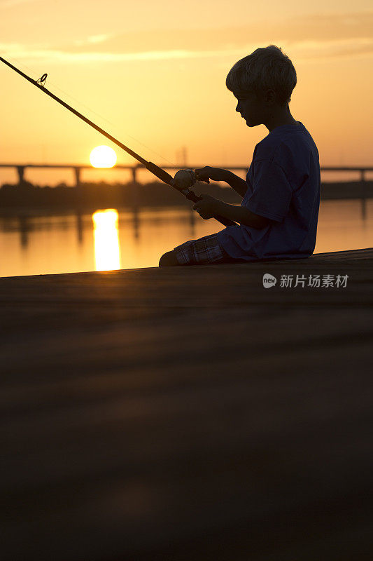 日出或日落，码头上的男孩在钓鱼