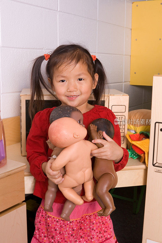 小女孩在幼儿园里抱着洋娃娃