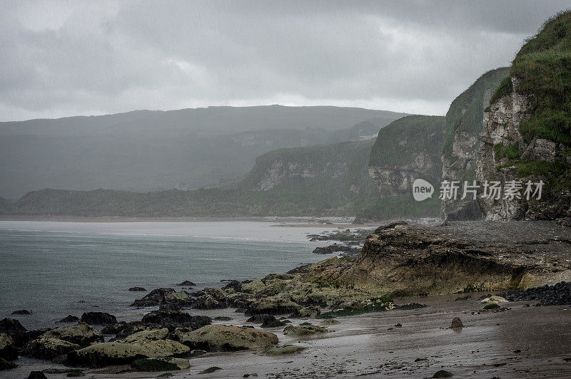 岩石海滩，悬崖和海岸线在雨中