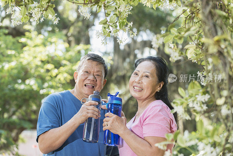 年老的亚洲夫妇在公园里喝水