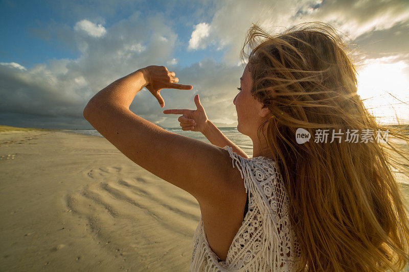 年轻女子用手指描绘海滩风景