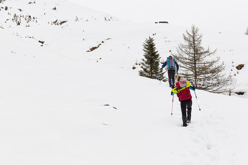 徒步旅行者在白雪覆盖的山上行走