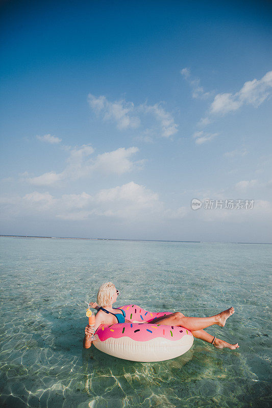 性感的女人浮在水上，有鸡尾酒时间在海洋，马尔代夫