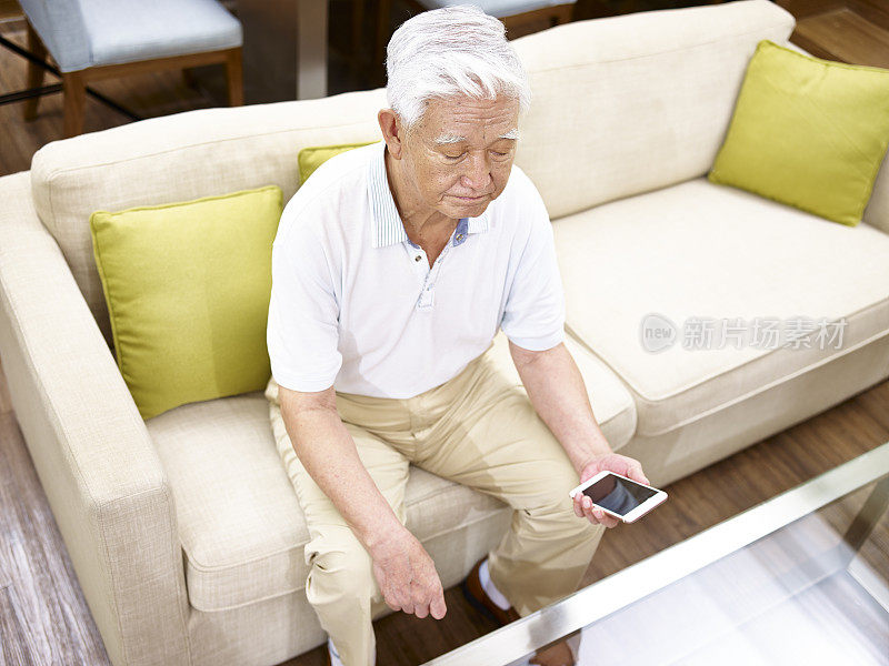 年长的亚洲人拿着手机