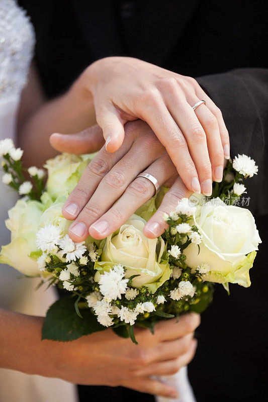 新婚夫妇手持结婚戒指和花束