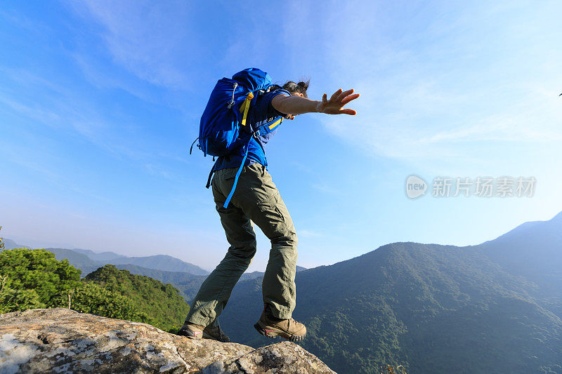 勇敢的女性徒步旅行者走到山顶的悬崖边缘