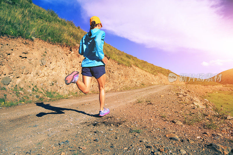 年轻的健身女运动员在山间小径上跑步