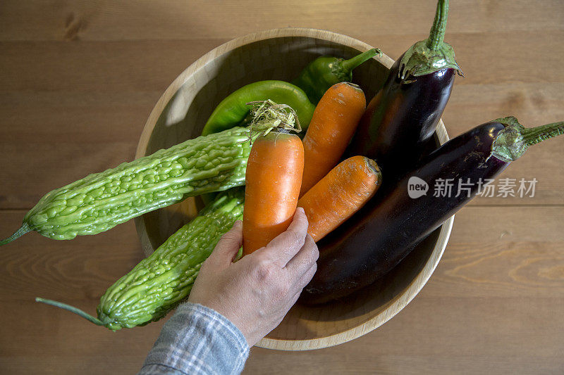 用手拿起木碗里的蔬菜