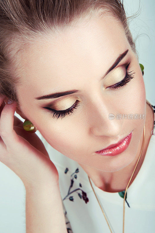 美丽性感的女人与自然日化妆戴绿色耳环