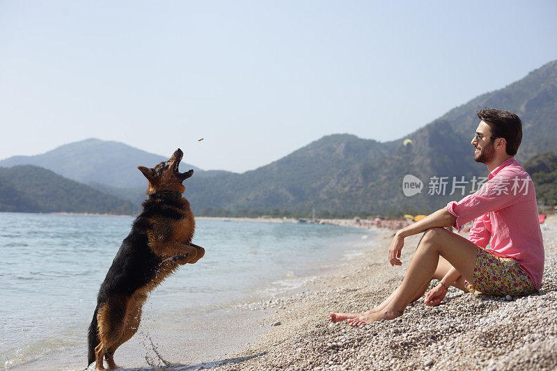 这个年轻人在费特耶Ölüdeniz海岸和她的狗在一起