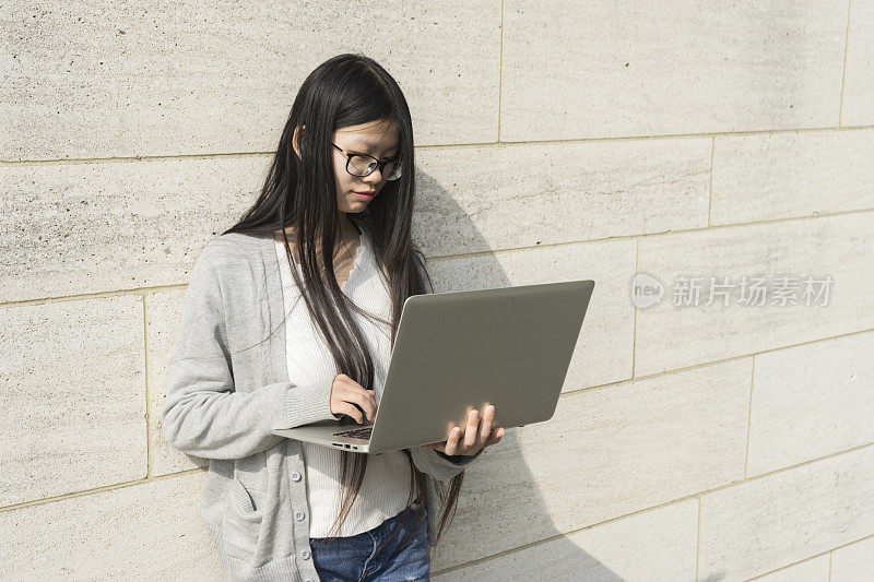 靠在水泥墙上上网的女人