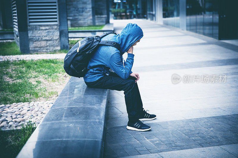 一个悲伤的人坐在城市的街道上