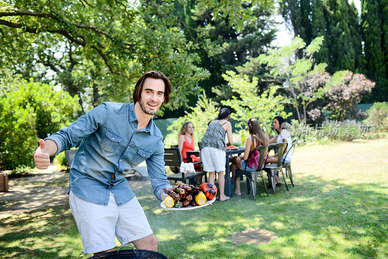 暑假期间，一帅哥在花园户外烧烤聚会上做饭