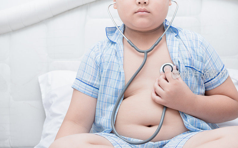 胖男孩用听诊器检查心脏，