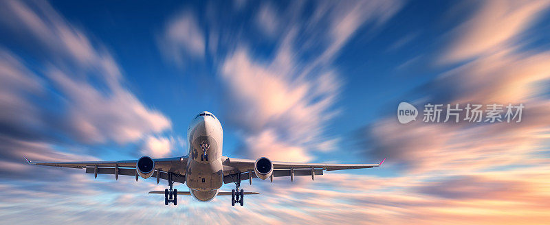 飞机和美丽的天空与运动模糊效果。落日时分，飞机和彩云在模糊的蓝天中飞翔。客运班机。商用飞机。私人飞机