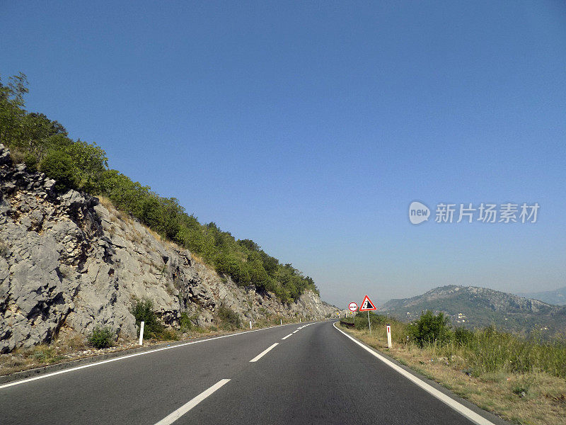 高速公路在山石嶙峋的景观中设有禁止超车和石头坠落的路标