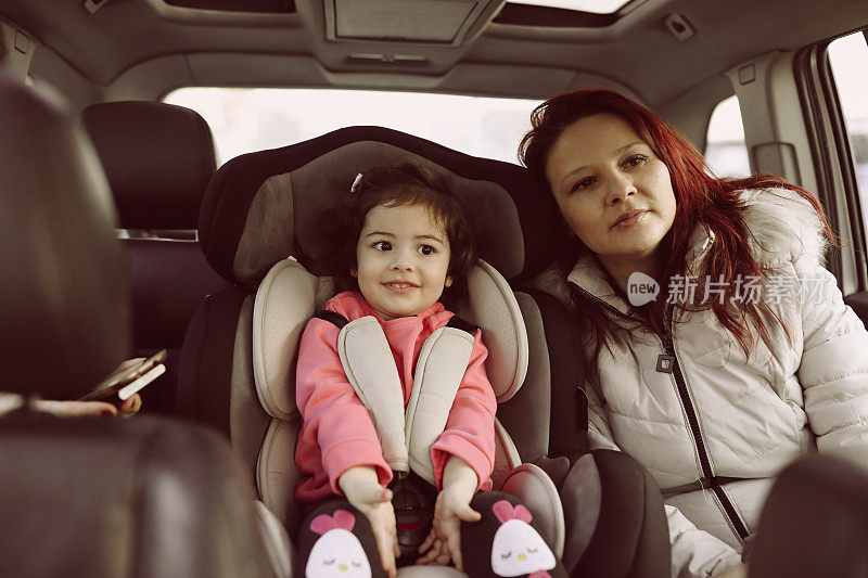 妈妈和小女儿坐在车后座上