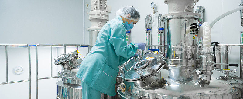 制药厂女工在无菌环境下操作防护服生产线