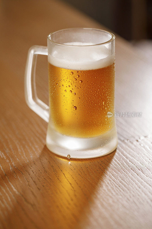 冰冷的啤酒杯中覆盖着凝结的水滴，背景是古老的复古酒吧