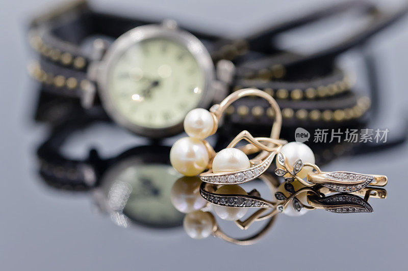 黄金耳环与珍珠在手表的背景