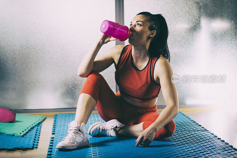 精疲力竭的女人在运动训练后喝水