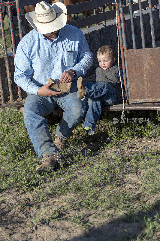 牛仔爸爸帮小儿子穿靴子