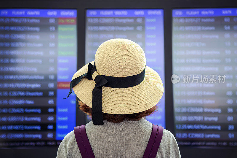 美丽的亚洲女性旅行者在航班信息屏幕