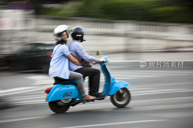 在法国巴黎，一对年轻夫妇骑着摩托车