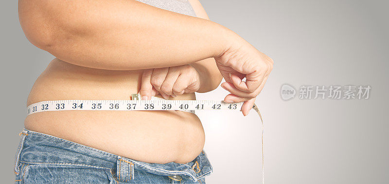 拿着卷尺的胖女人。体脂百分比用卷尺测量脂肪。