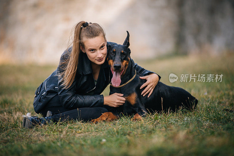 美丽的女人玩她的杜宾犬