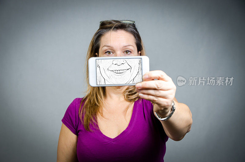 一个女人的手机在她面前，她的脸出现在屏幕上的图画