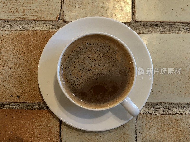 咖啡杯和茶碟放在瓷砖桌上
