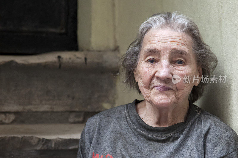 一位老妇人坐在路边的台阶上