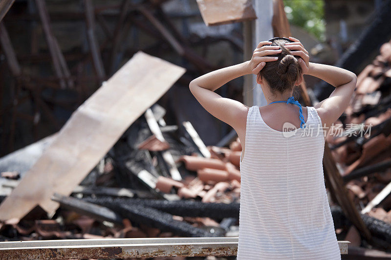 一个女人站在烧毁的房子前