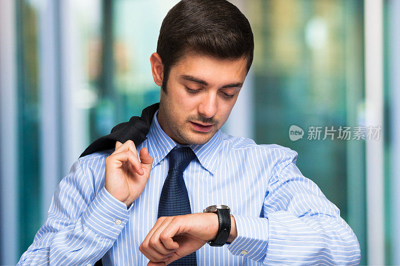 商人在条纹衬衫检查时间在手表