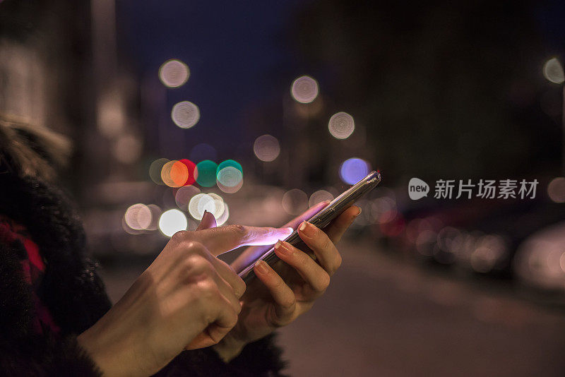 女人用手机，城市天际线夜光背景