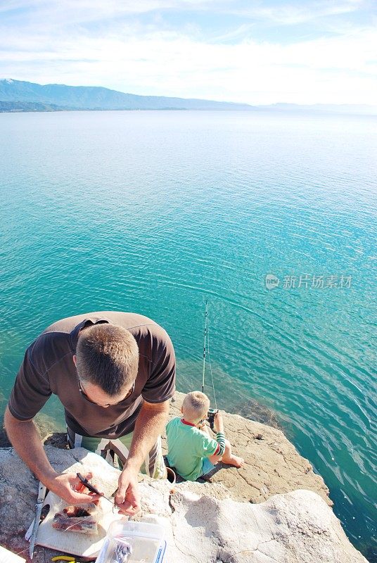 一个父亲和他的孩子在海岸岩石上钓鱼