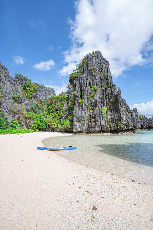 独木舟在热带泻湖的海滩上，周围有石灰岩尖塔。旅游目的地度假自然的概念