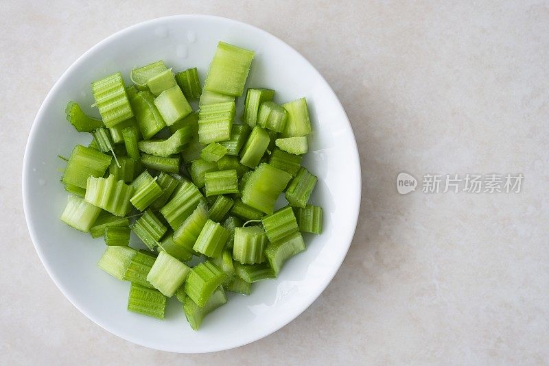 白色盘子里切碎的芹菜