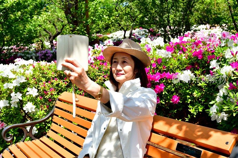 一名日本女子在公园里与盛开的杜鹃花自拍