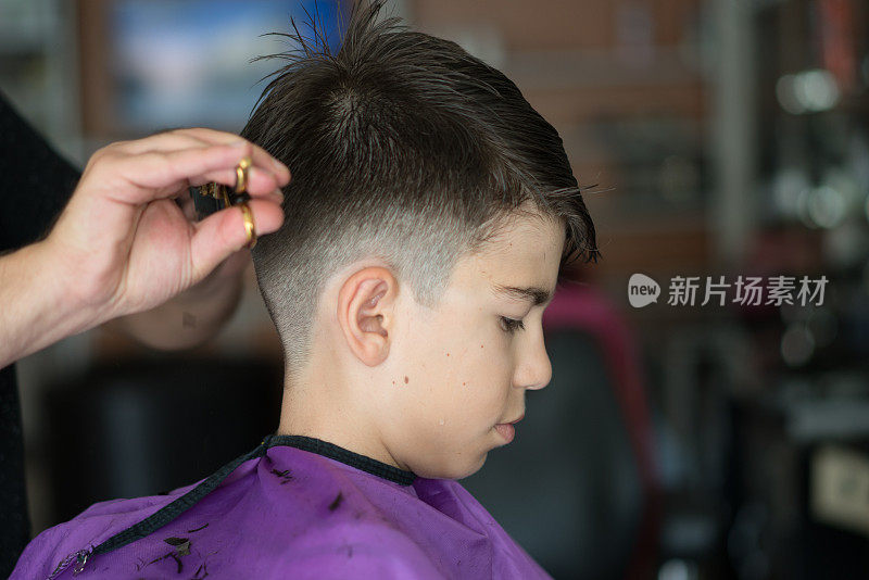 在一家现代化的理发店里，理发师为那个男孩做了一个时髦的漂亮发型