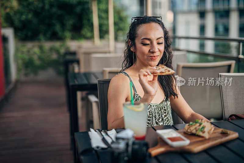 一位女士独自坐在餐馆外面吃午饭