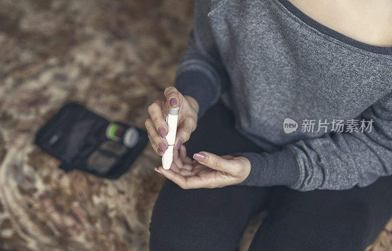 年轻女性用血糖仪检测高血糖的手的特写。糖尿病的控制