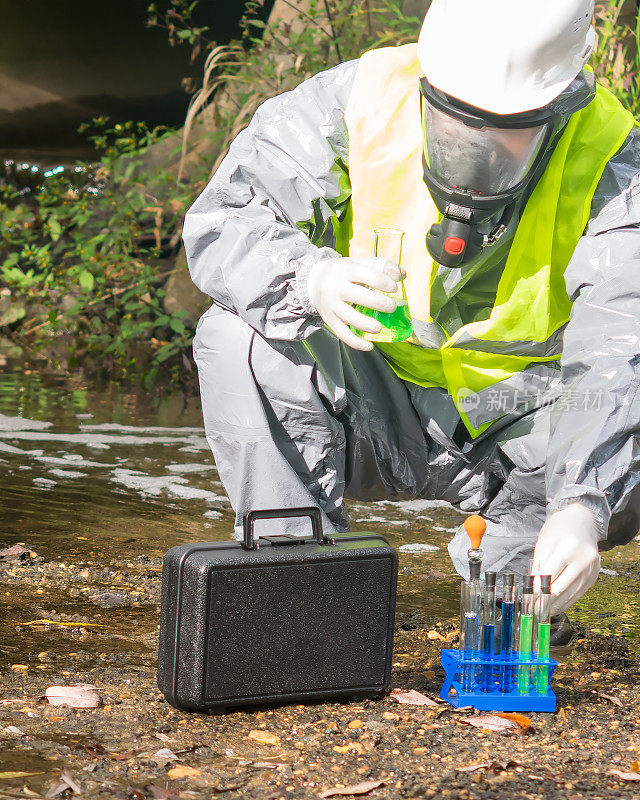 实验室助理穿着防护服和面罩，带一间小型实验室，在据称的环境污染现场进行快速测试